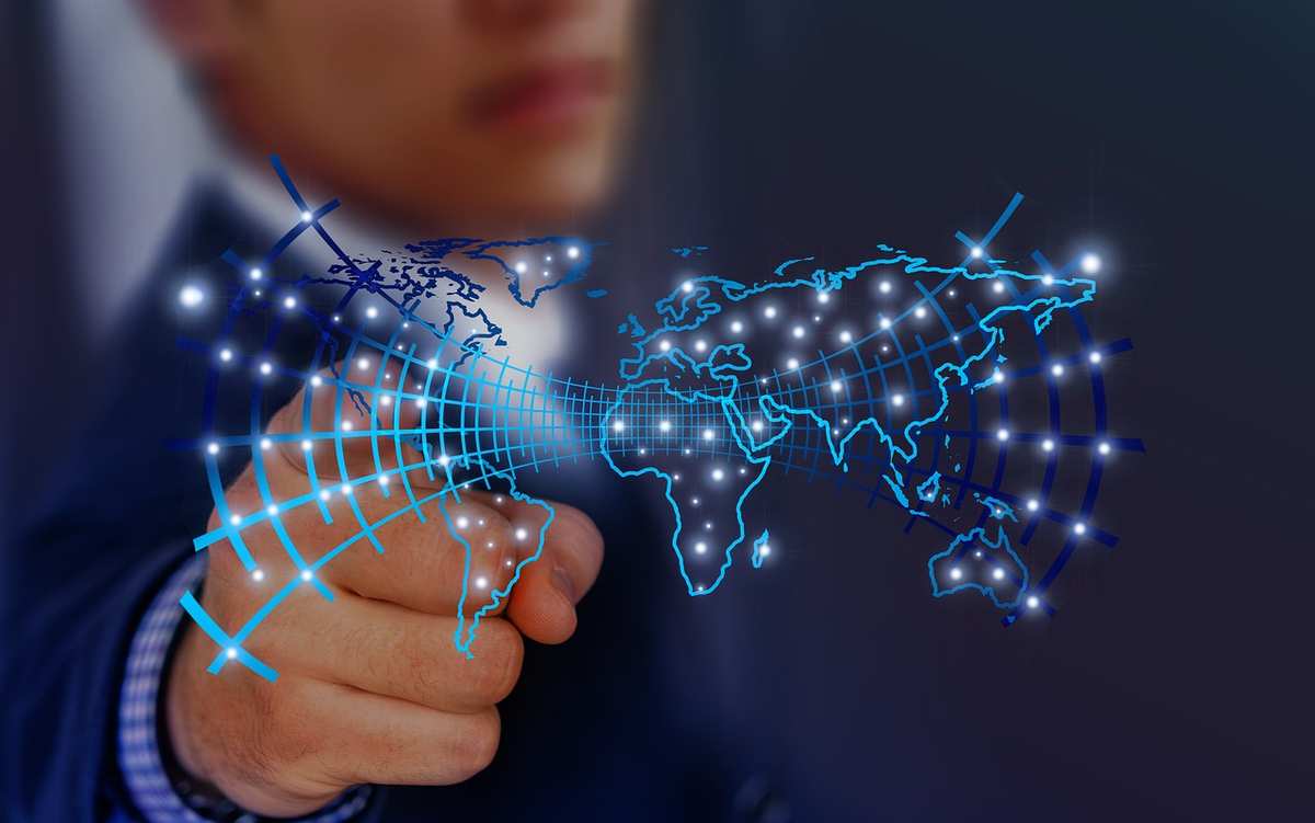 Hand touching a glowing digital world map, representing connected networks